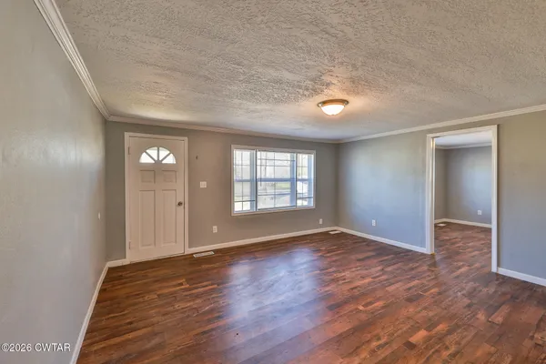 a view of an empty room with window and wooden floor