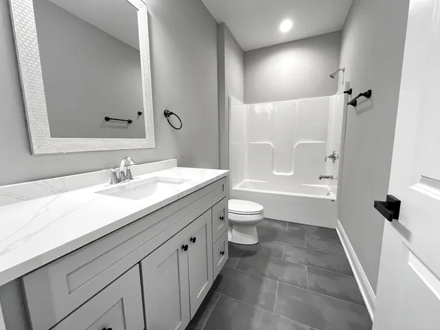 a bathroom with a granite countertop sink a toilet and shower