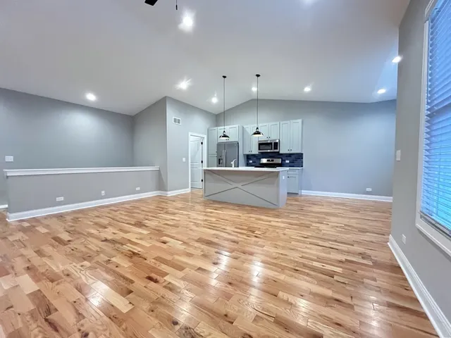 a view of kitchen and empty room with wooden floor