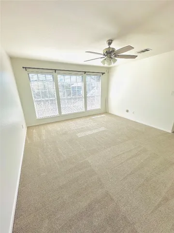 an empty room with windows and fan