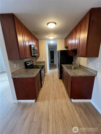 a large kitchen with wooden floors stainless steel appliances a counter space and a window