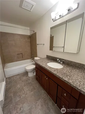 a bathroom with a granite countertop sink a toilet a mirror and bathtub
