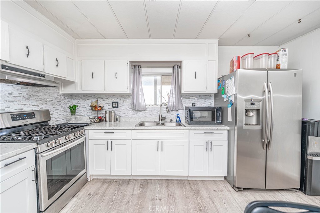 a kitchen with stainless steel appliances a white cabinets and a stove top oven