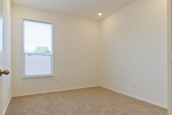 an empty room with a chandelier fan and windows