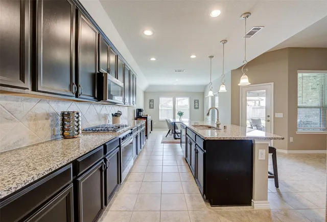 a kitchen with granite countertop stainless steel appliances a sink counter top space cabinets and a window