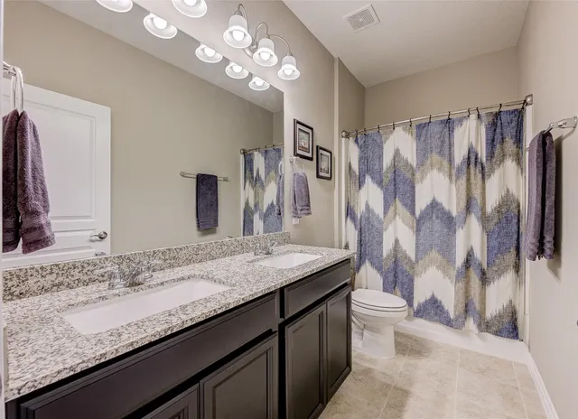 a bathroom with a granite countertop sink a toilet and a mirror