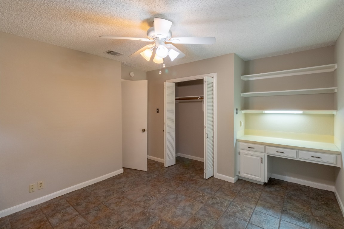 5839 Secrest Drive Austin, TX 78759 - Photo 11 of 34 Unfurnished bedroom with built in study area, a closet, a textured ceiling, and a ceiling fan