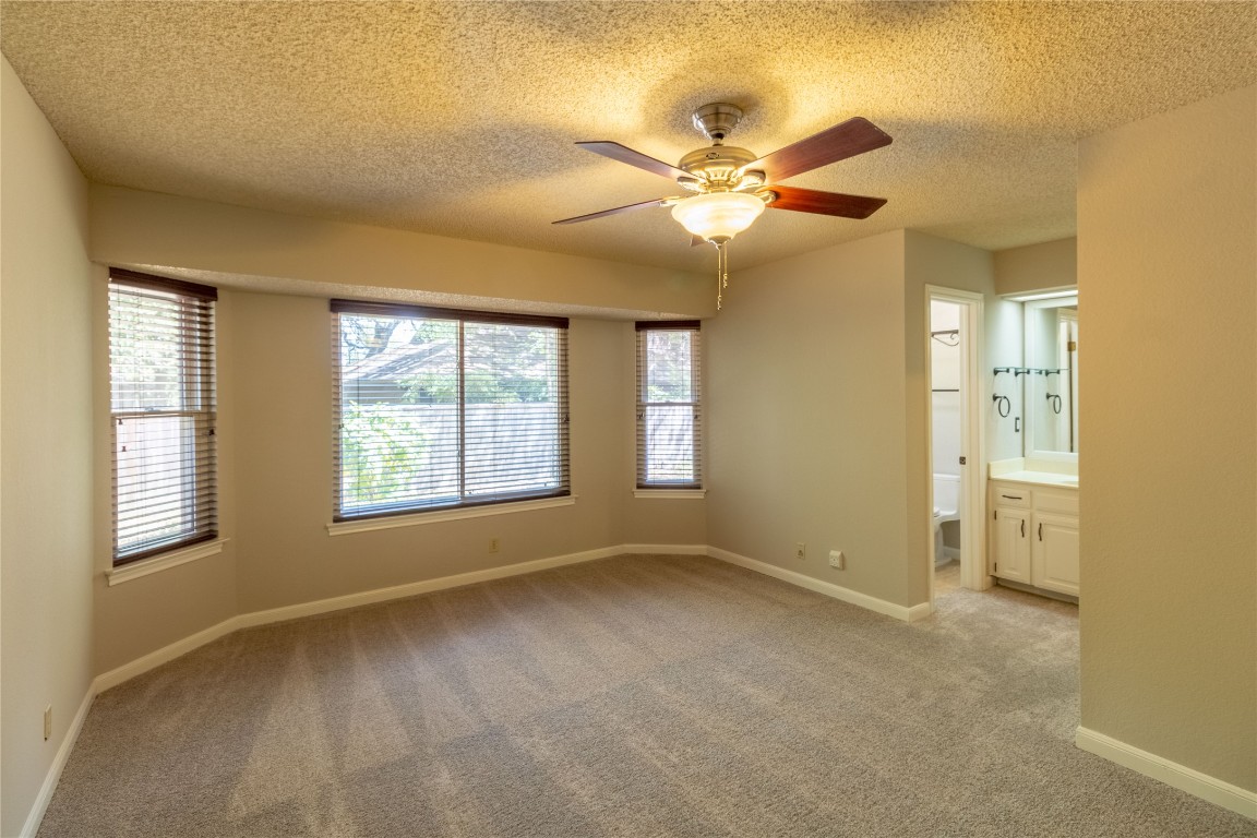5839 Secrest Drive Austin, TX 78759 - Photo 15 of 34 Empty room featuring light carpet, plenty of natural light, ceiling fan, and a textured ceiling