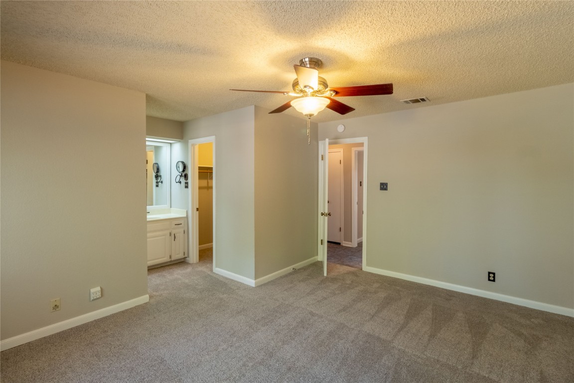 5839 Secrest Drive Austin, TX 78759 - Photo 16 of 34 Unfurnished bedroom featuring light colored carpet, a textured ceiling, a walk in closet, ceiling fan, and a closet