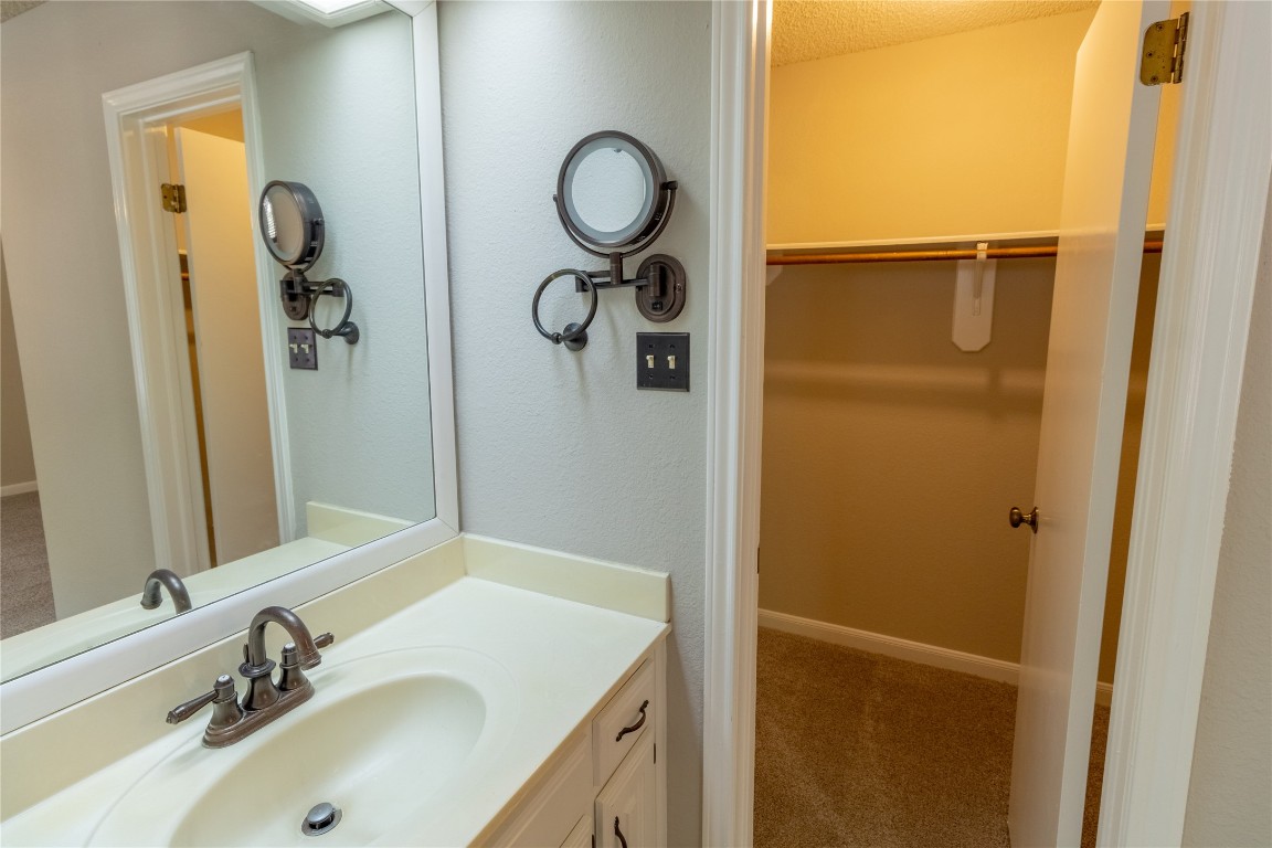 5839 Secrest Drive Austin, TX 78759 - Photo 19 of 34 Bathroom with vanity, a spacious closet, and a textured ceiling