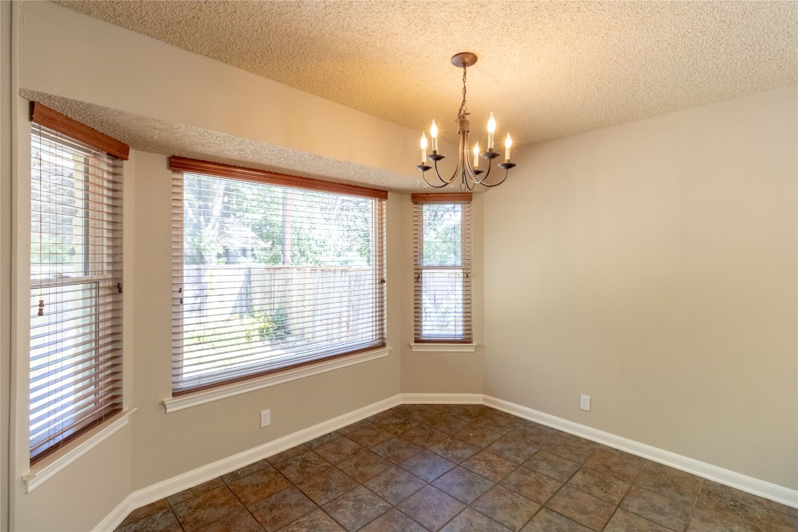 5839 Secrest Drive Austin, TX 78759 - Photo 20 of 34 Spare room featuring a chandelier and a textured ceiling
