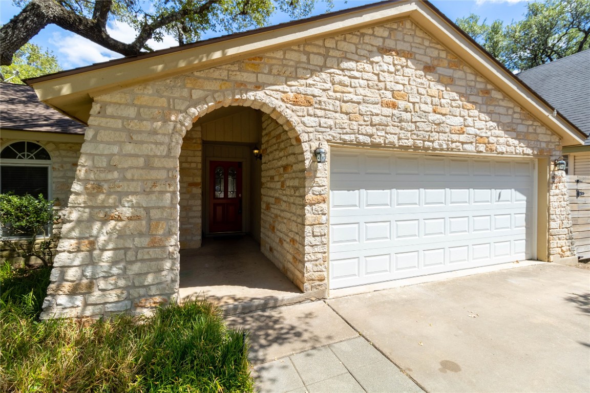 5839 Secrest Drive Austin, TX 78759 - Photo 2 of 34 View of front of property featuring stone siding, an attached garage, roof with shingles, and driveway