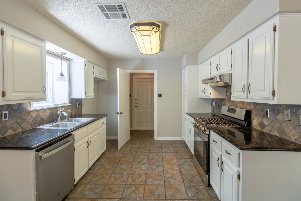 5839 Secrest Drive Austin, TX 78759 - Photo 23 of 34 Kitchen with appliances with stainless steel finishes, under cabinet range hood, dark countertops, decorative backsplash, and a textured ceiling