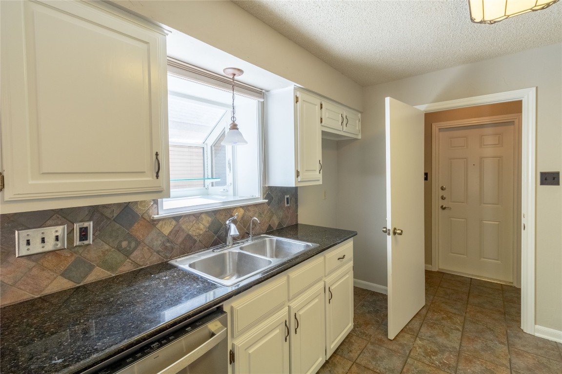 5839 Secrest Drive Austin, TX 78759 - Photo 25 of 34 Kitchen with dishwasher, dark countertops, decorative backsplash, a textured ceiling, and decorative light fixtures