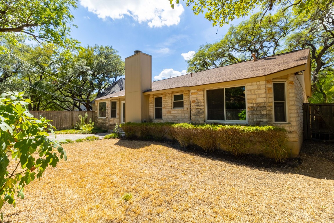 5839 Secrest Drive Austin, TX 78759 - Photo 30 of 34 Back of property with stone siding, a chimney, and roof with shingles