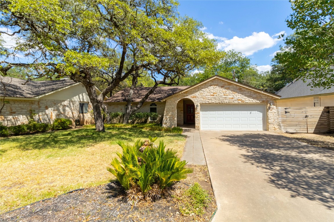 5839 Secrest Drive Austin, TX 78759 - Photo 3 of 34 View of front facade featuring an attached garage, concrete driveway, a front lawn, and stone siding
