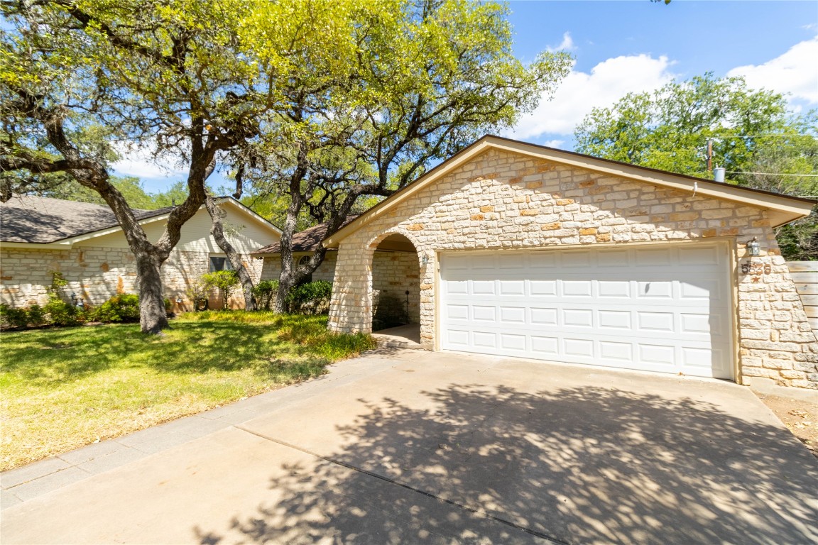 5839 Secrest Drive Austin, TX 78759 - Photo 6 of 34 View of front of home with stone siding, concrete driveway, a front lawn, and a garage