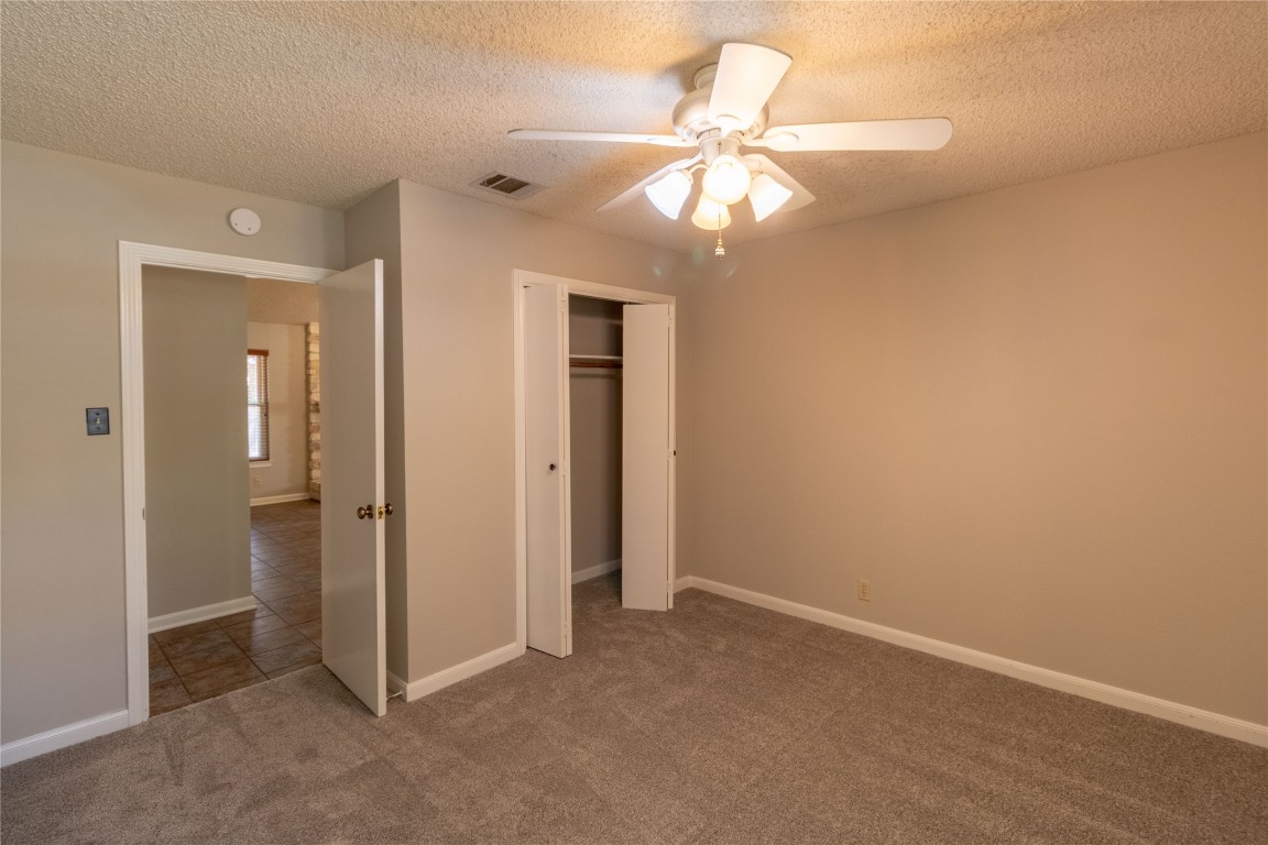 5839 Secrest Drive Austin, TX 78759 - Photo 8 of 34 Unfurnished bedroom featuring carpet floors, a textured ceiling, a closet, and a ceiling fan