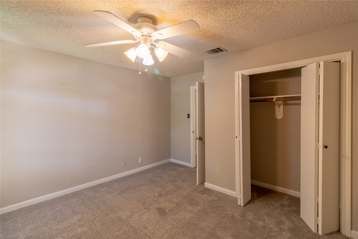 5839 Secrest Drive Austin, TX 78759 - Photo 9 of 34 Unfurnished bedroom featuring carpet floors, a closet, a textured ceiling, and ceiling fan