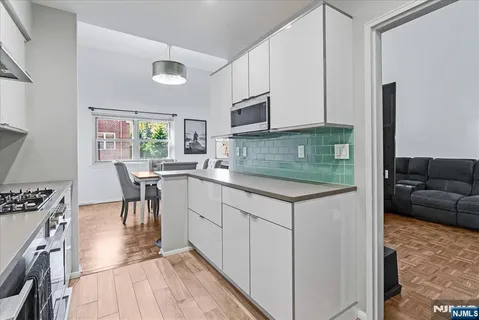 a kitchen with stainless steel appliances granite countertop a stove top oven a sink a dining table and chairs with wooden floor