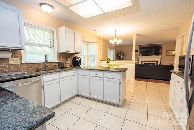 a large kitchen with a stove a sink dishwasher and a microwave oven with white cabinets