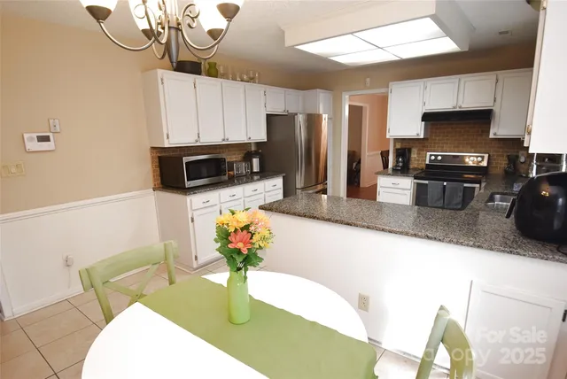 a kitchen with stainless steel appliances granite countertop a sink a stove a microwave a refrigerator a counter top space and cabinets