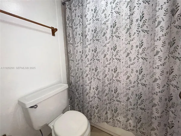 a white toilet sitting next to a shower curtain