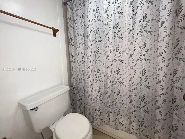 a white toilet sitting next to a shower curtain