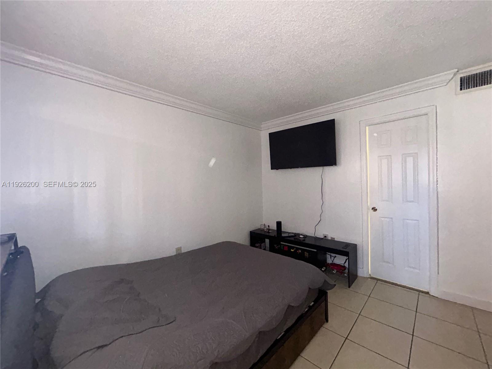 19805 Southwest 114th Avenue, Unit 219 Miami, FL 33157 - Photo 9 of 12 a bedroom with a bed and a flat screen tv