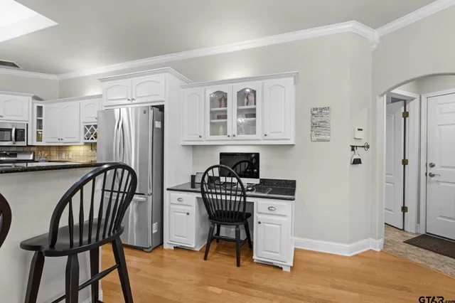 a kitchen with stainless steel appliances granite countertop a dining table chairs and a refrigerator