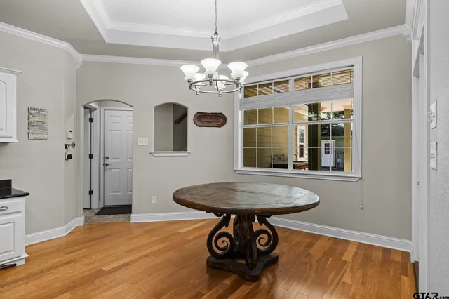 a dining room with chandelier and wooden floor