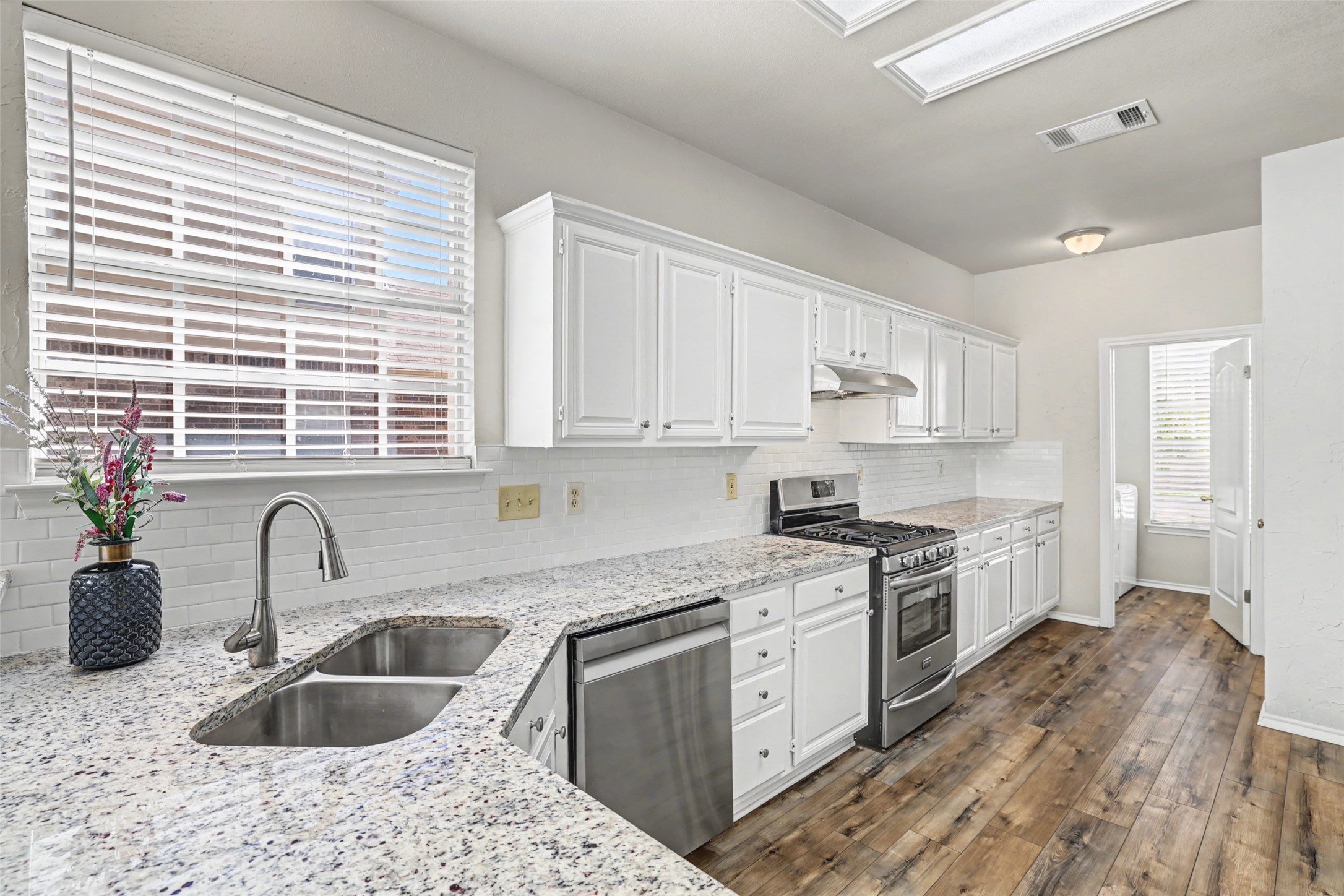 1109 Pebble Brook Road Cedar Park, TX 78613 - Photo 14 of 40 Kitchen with stainless steel appliances, backsplash, white cabinetry, dark wood-type flooring, and light stone counters