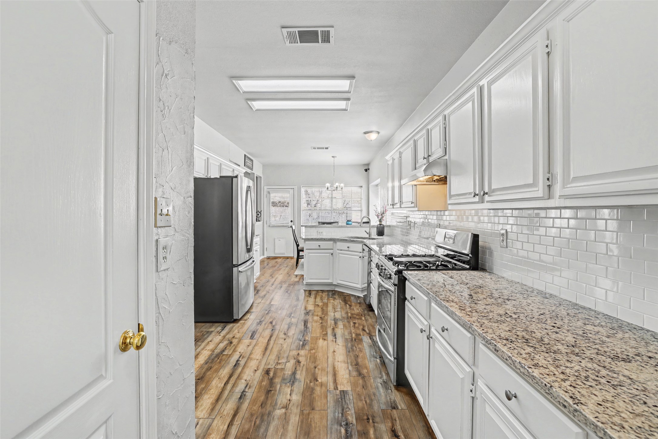 1109 Pebble Brook Road Cedar Park, TX 78613 - Photo 15 of 40 Kitchen featuring stainless steel appliances, white cabinetry, light wood-type flooring, and light stone counters
