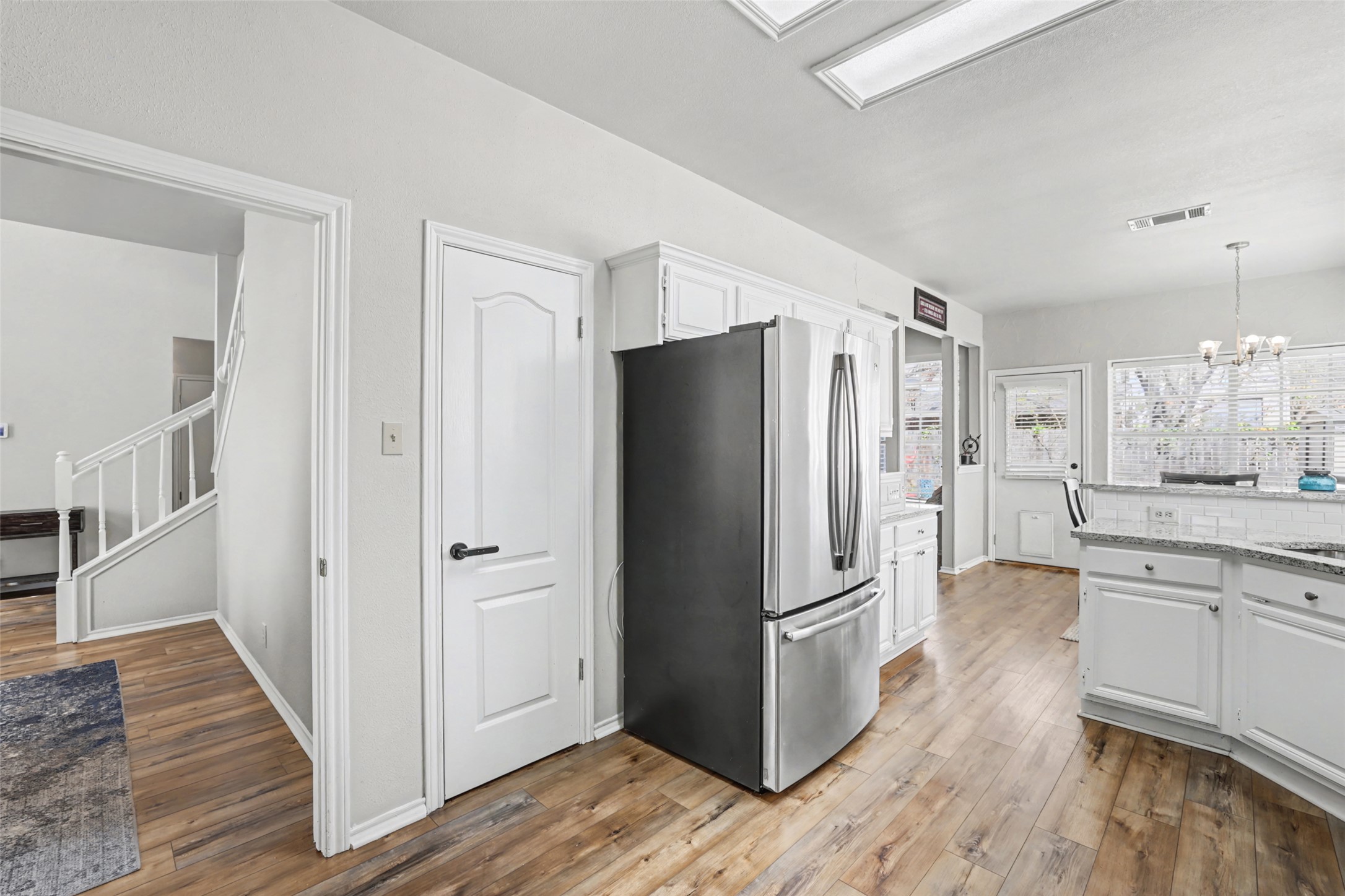1109 Pebble Brook Road Cedar Park, TX 78613 - Photo 16 of 40 Kitchen with white cabinets, freestanding refrigerator, light wood-style floors, a chandelier, and light stone countertops