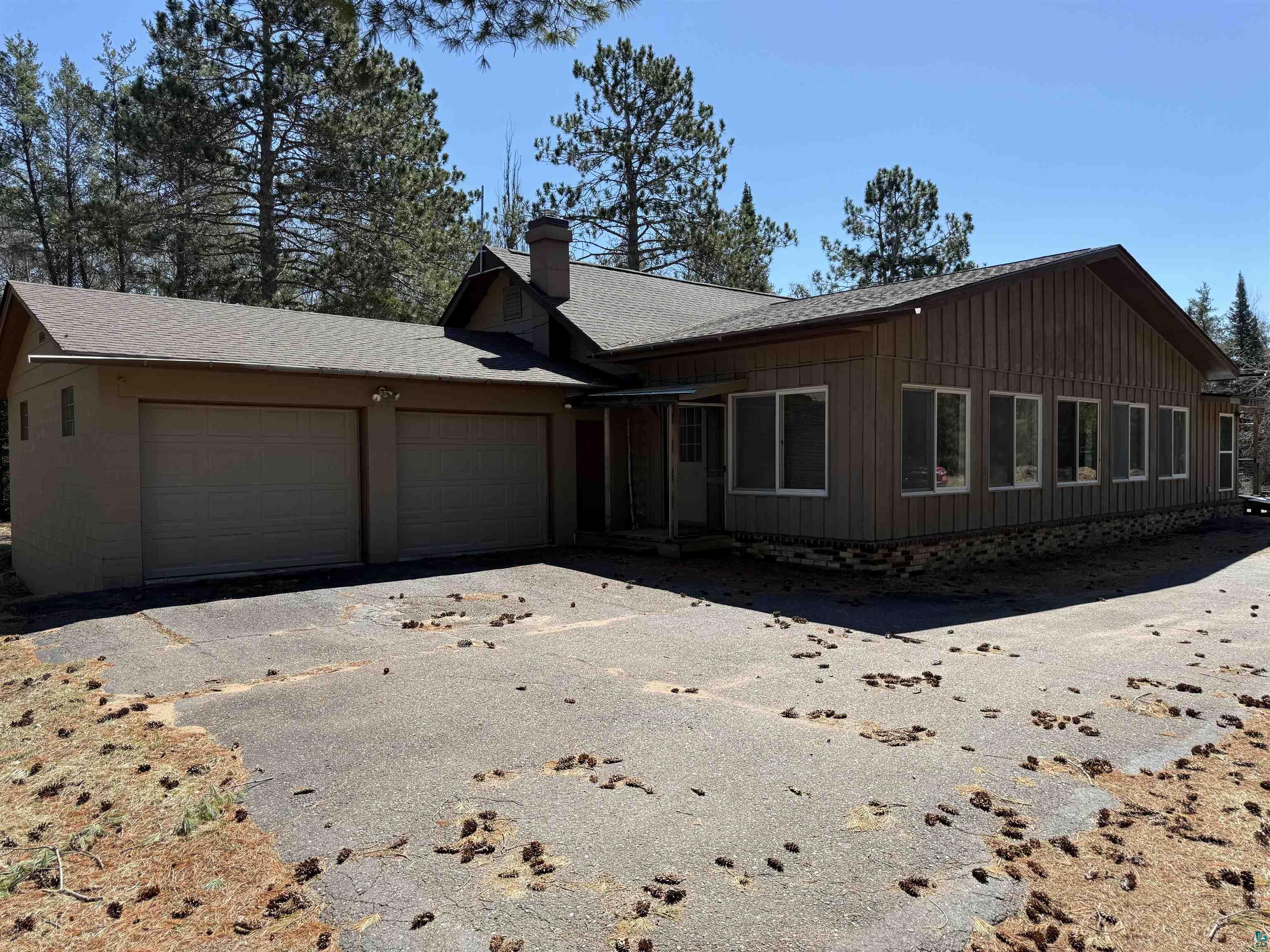 View of front of house featuring an attached garage, asphalt driveway, roof with shingles, and a chimney