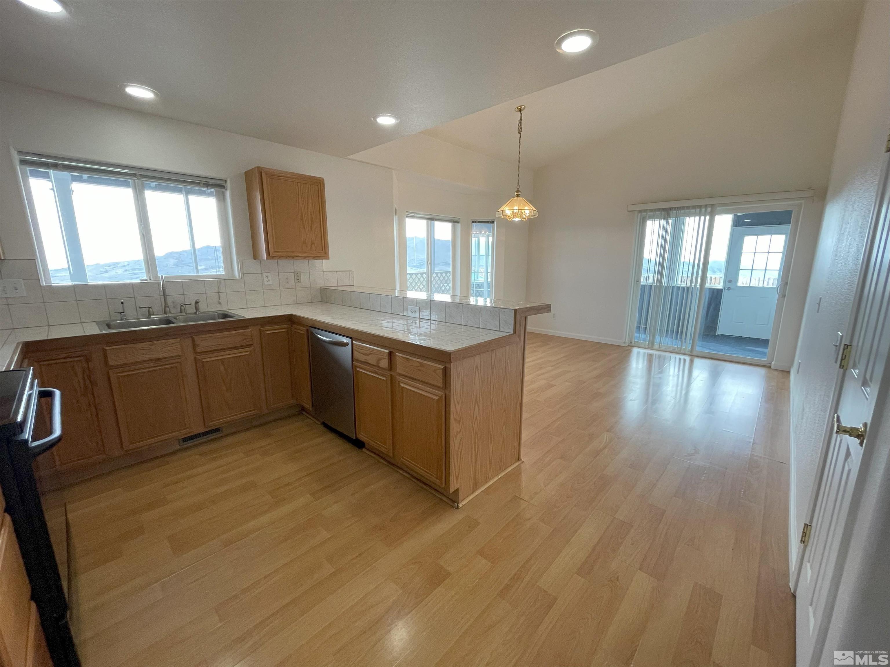 15064 North Red Rock Road Reno, NV 89508 - Photo 4 of 40 a large kitchen with stainless steel appliances granite countertop a sink and cabinets with wooden floor