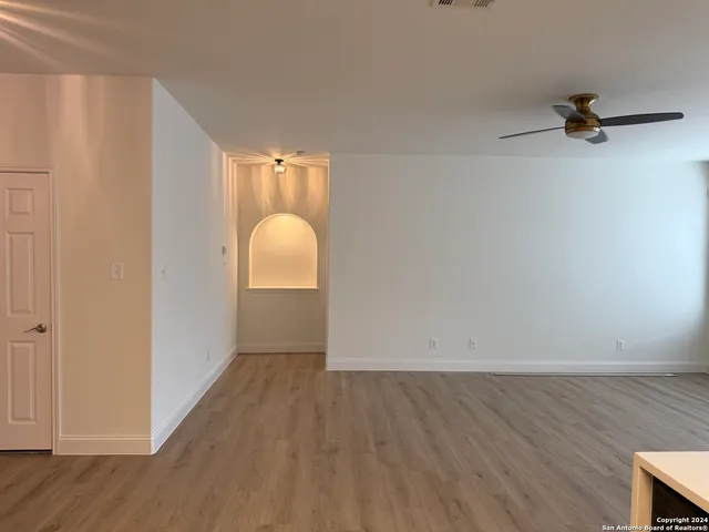 an empty room with wooden floor mirror and windows