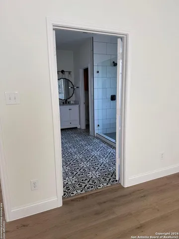 a view of an empty room with wooden floor and a bathroom