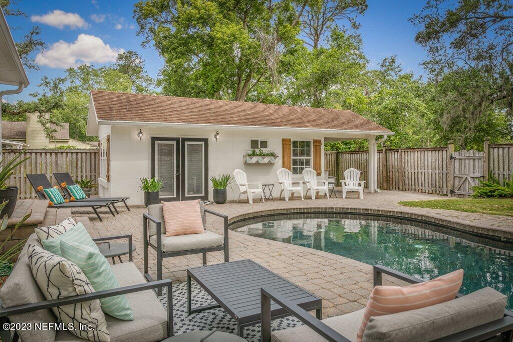 1623 Charon Road Jacksonville, FL 32205 - Photo 21 of 45 a view of a patio with couches table and chairs under an umbrella with large trees and wooden fence