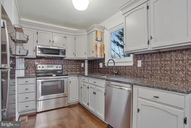 a kitchen with stainless steel appliances granite countertop a stove a sink and a microwave