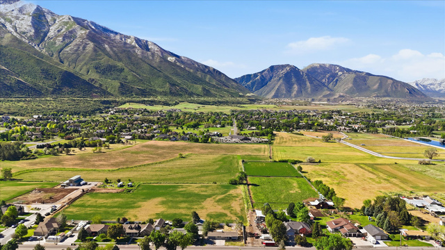 810 East Maple Street Mapleton, UT 84664 - Photo 41 of 49 Expansive aerial perspective showcasing a mountainous backdrop, verdant fields, a residential area, and a visible body of water