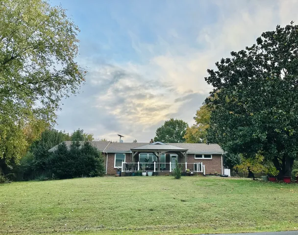 a view of a house with a big yard and large trees