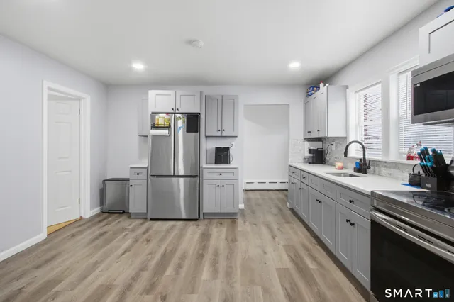 a kitchen with a sink wooden floor and stainless steel appliances