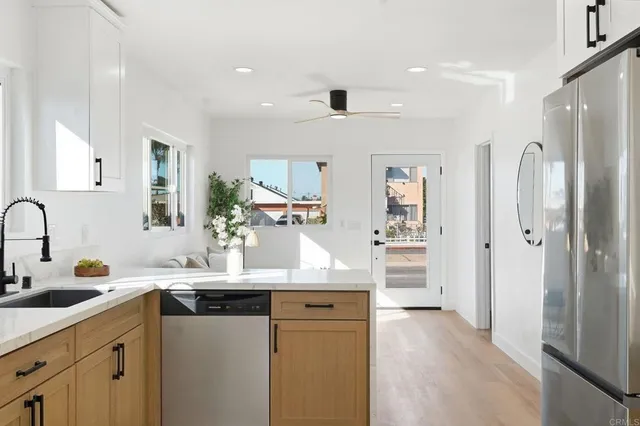 a kitchen with granite countertop a sink a stove a refrigerator and white cabinets with wooden floor