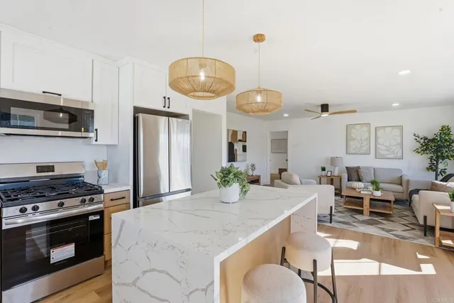 a kitchen with stainless steel appliances granite countertop a stove a refrigerator a kitchen island a dining table and chairs