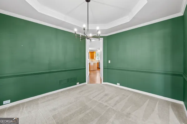 an empty room with chandelier fan and window