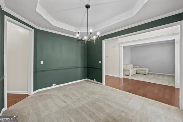 a view of an empty room with chandelier fan