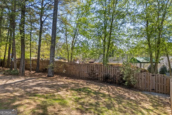a view of a yard with large trees and wooden fence