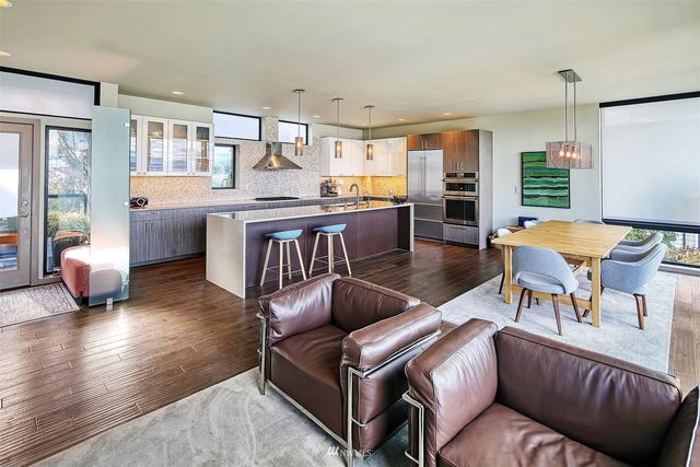 a kitchen with stainless steel appliances granite countertop a kitchen island hardwood floor sink stove dining table and chairs