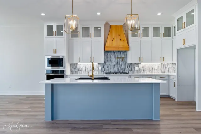 a kitchen with stainless steel appliances granite countertop a sink dishwasher a stove and a microwave oven with white cabinets